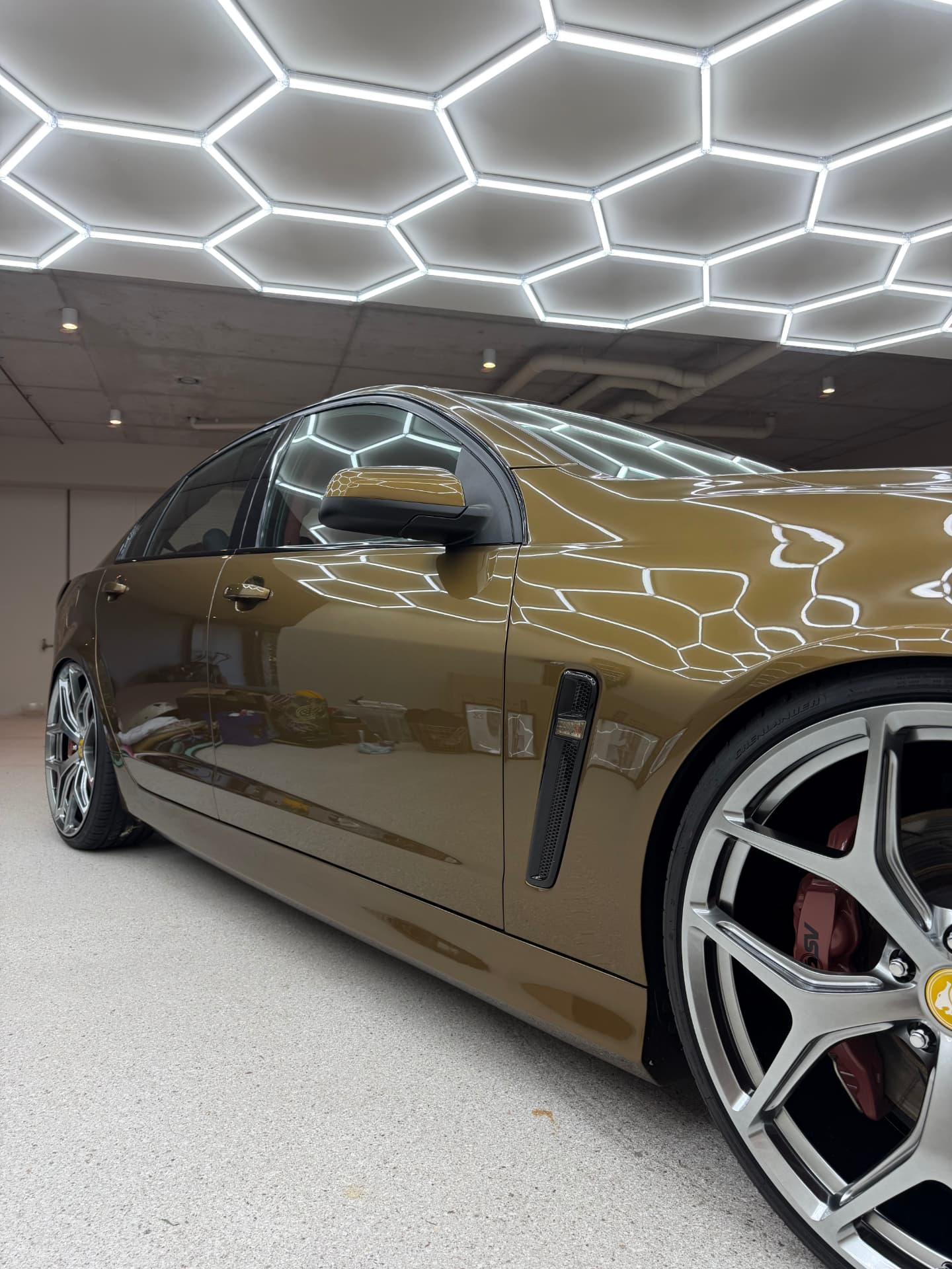 Holden Commodore with a mirror-gloss finish reflecting a hexagon LED ceiling